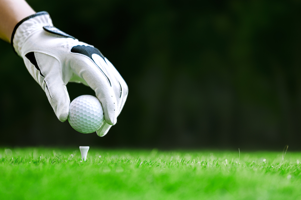 player placing golf ball on tee